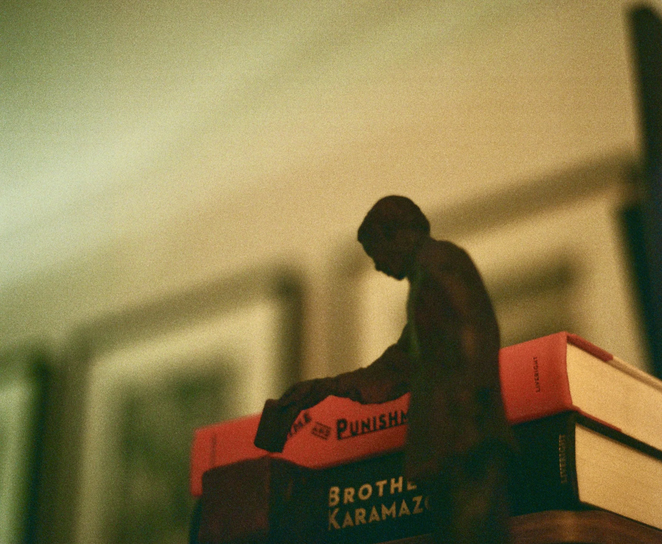 A small seated figure resting on a stack of books