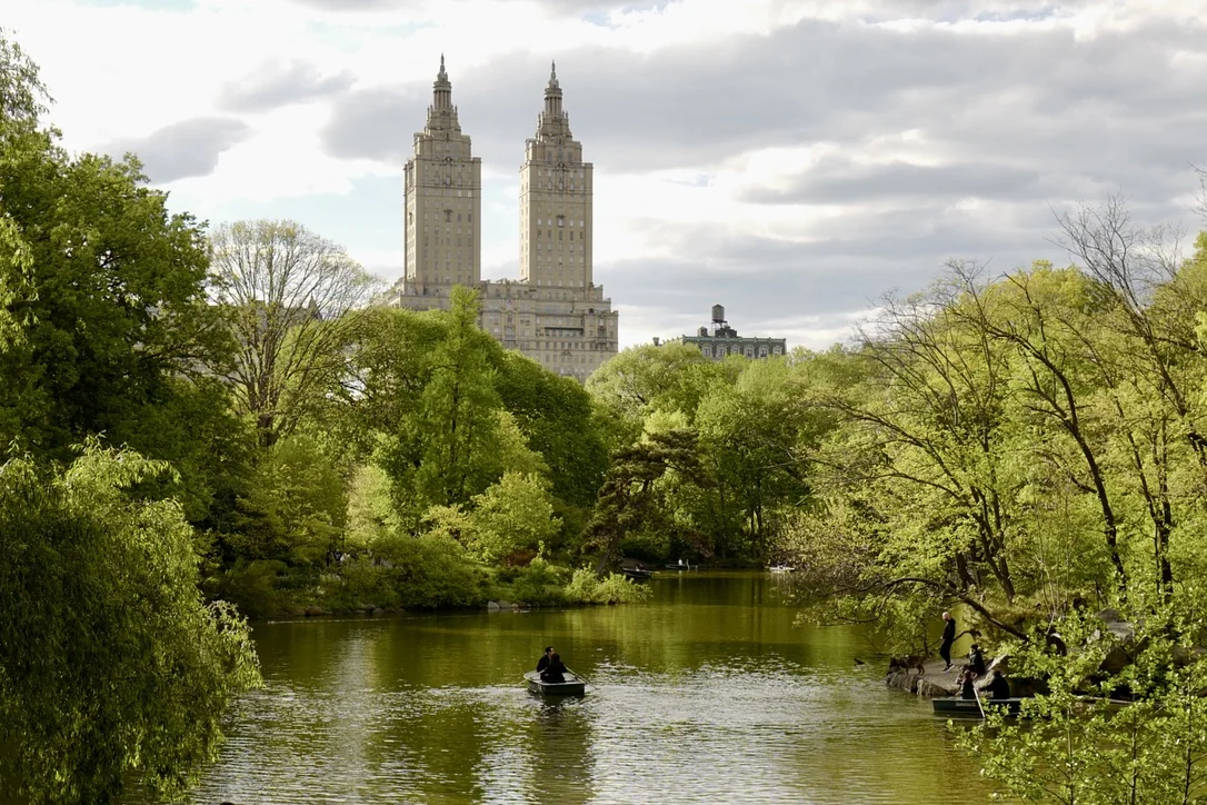 Rowboats crossing the lake in Central Park beneath the San Remo towers